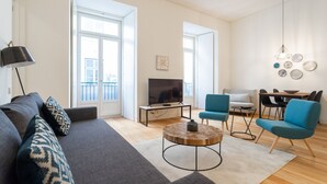 A modern living room with a sofa, coffee table, and blue chairs. - FLH Chiado Modern Apartment (Lisbon)