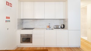 A modern kitchen with white cabinets, a built-in oven, a sink, and a toaster. - FLH Chiado Modern Apartment (Lisbon)