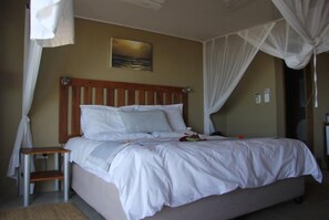 A neatly made bed with white linens, a wooden headboard, and a small bedside table with a lamp.