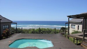 A wooden deck with a swimming pool, overlooking the ocean.