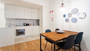 Une cuisine moderne avec des meubles blancs, une table à manger en bois et une machine à café.