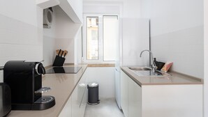 Eine kleine Küche mit einer Kaffeemaschine, einem Spülbecken und einem Mülleimer.