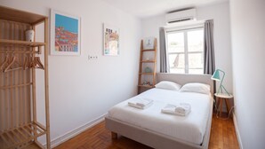 A hotel room with a bed, a wardrobe, a window with curtains, and wall art.