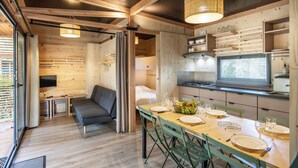 A compact kitchen with a dining area, wooden walls, and a modern pendant light. - Camping de l'Ill Colmar (Horbourg-Wihr)