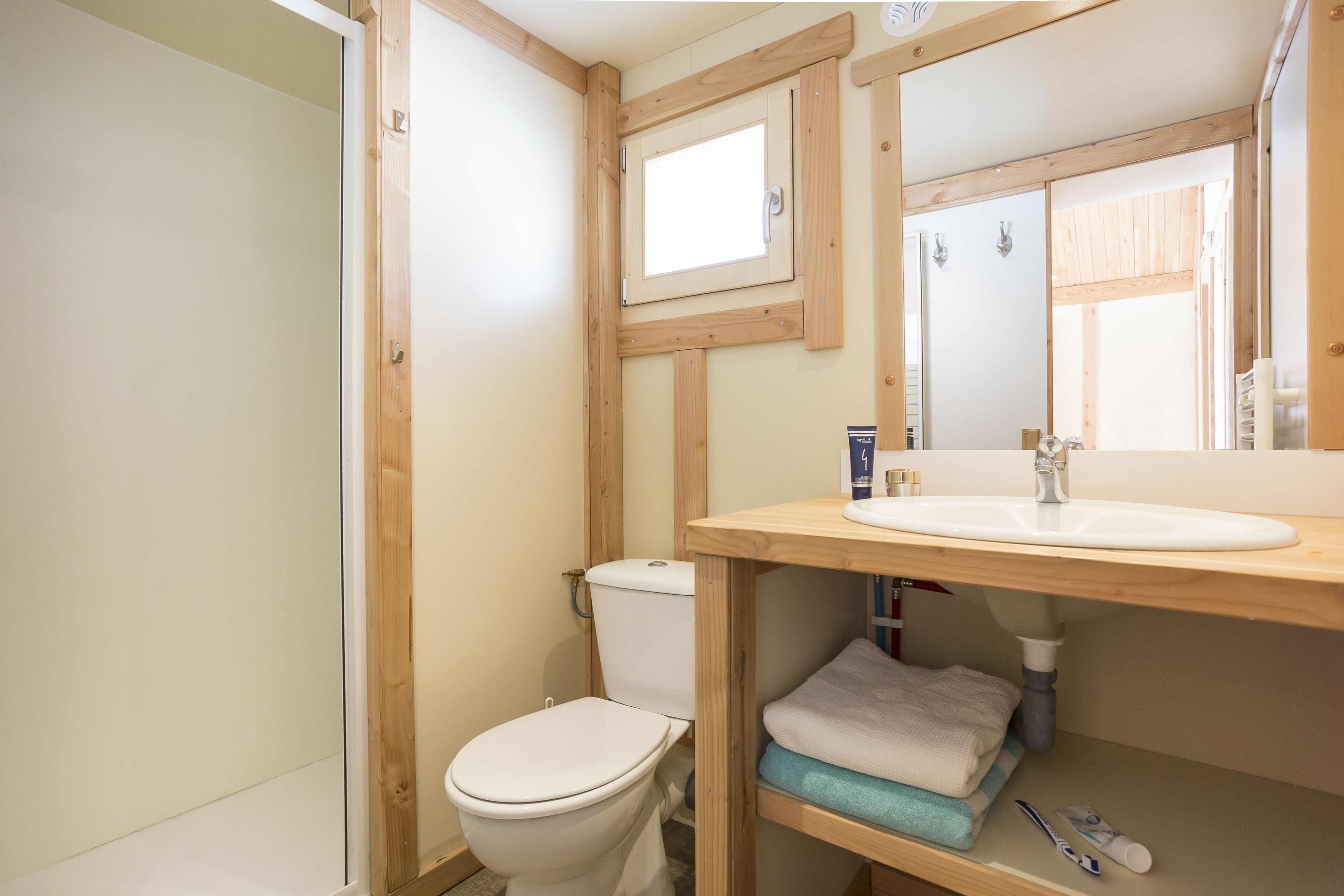 A bathroom with a wooden vanity, a toilet, and a window.