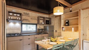 A compact kitchen with wooden cabinetry, a built-in stove, and a dining area with a wooden table and chairs. - Camping de l'Ill Colmar (Horbourg-Wihr)