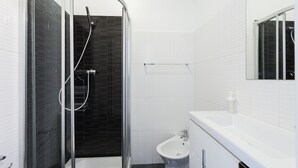 Un baño moderno con ducha de vidrio, lavamanos blanco y espejo.