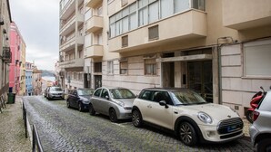 Una calle adoquinada flanqueada por coches aparcados y edificios de varios pisos.