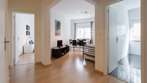 Un amplio espacio de sala con un sofá, sillas, un televisor y una mesa de comedor.