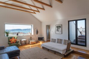 Une chambre spacieuse dotée d’une grande fenêtre, d’un lit, d’une chaise et offrant une vue sur la mer.