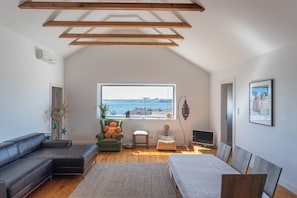 Une chambre de style loft moderne, dotée d’une grande fenêtre, d’un fauteuil vert, d’un canapé et d’un lit.