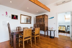 A dining area with a wooden table and chairs, a large mirror, and a cabinet. - FLH Chiado Skyline (Lisbon)