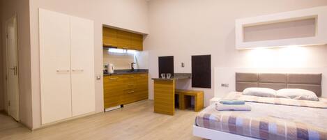 Un dormitorio con cama, mesitas de noche, armario y una zona de cocina integrada.