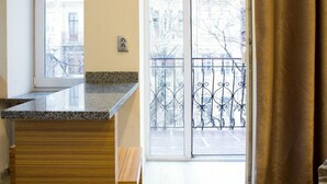 Una cocina moderna con encimera de granito, armarios de madera y una puerta corrediza de vidrio que da a un balcón con barandilla de metal.