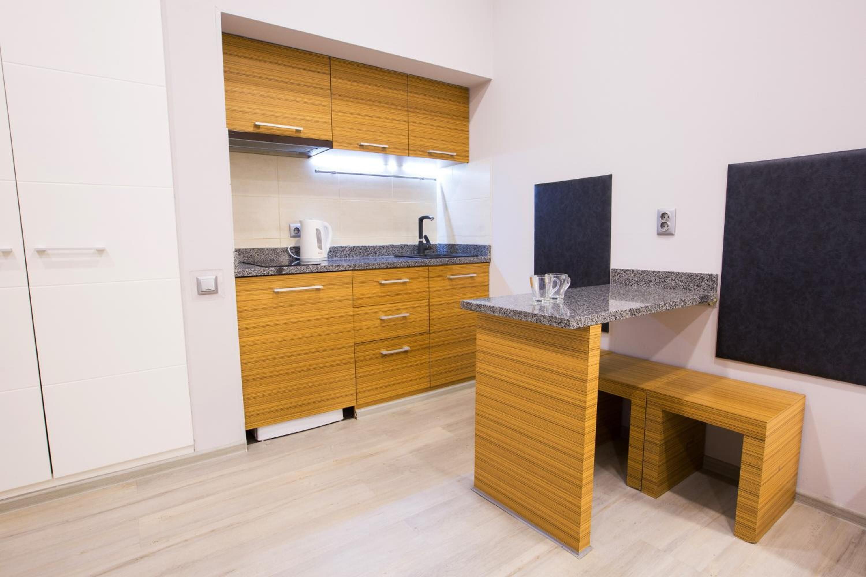 A compact kitchen with wooden cabinets, a granite countertop, and a built-in bench.