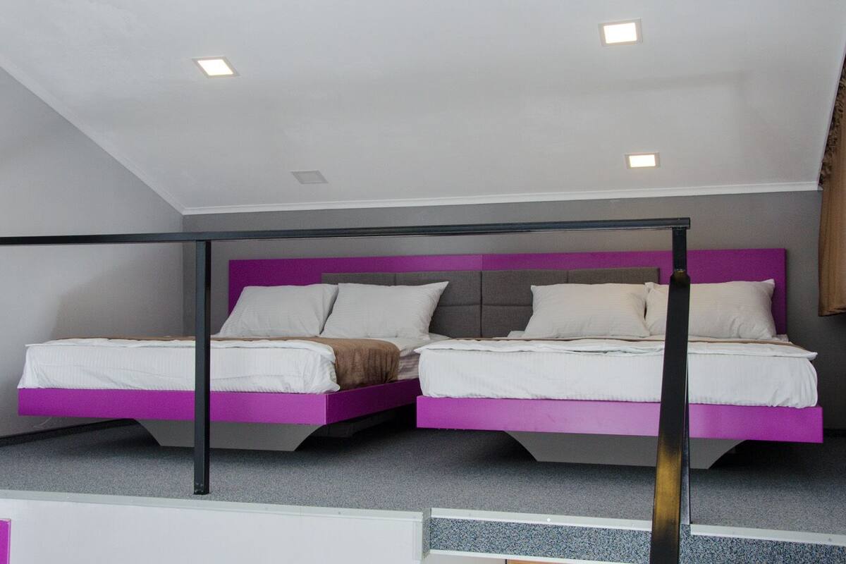 A bedroom with two beds, a sloped ceiling, and recessed lighting.