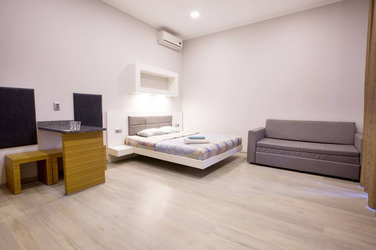 A modern bedroom with a bed, bedside table, and a sofa.