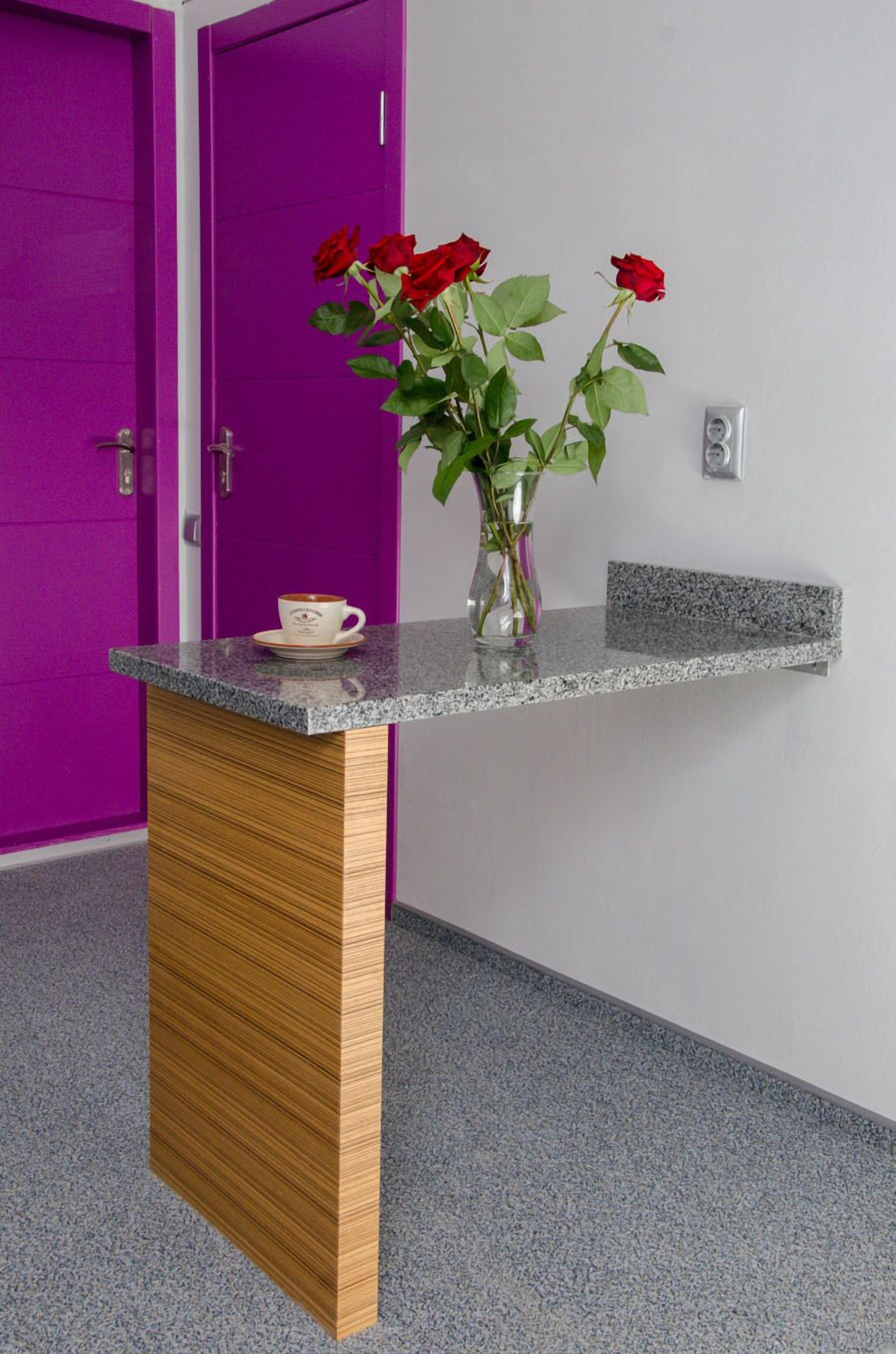 A reception desk with a vase of red roses and a coffee cup.