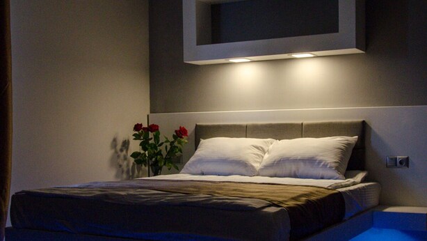 Un dormitorio moderno con una cama, un televisor de pared y un florero con flores.