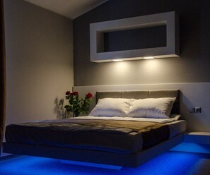 A modern bedroom with a bed, a wall-mounted TV, and a vase with flowers. - Pushkinskaya Apartments (Kharkiv)