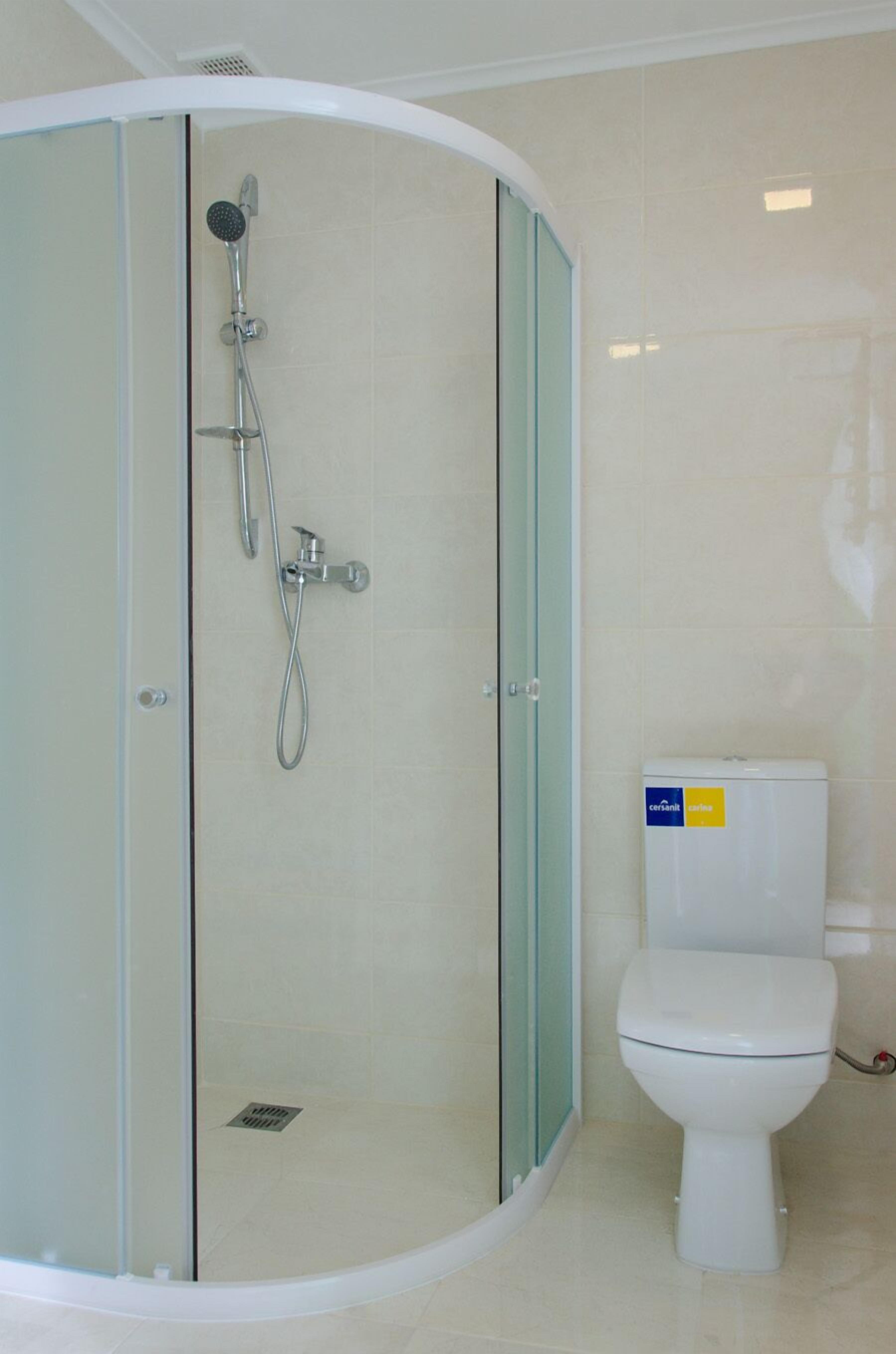 Un baño moderno con cabina de ducha de vidrio, inodoro y lavamanos.