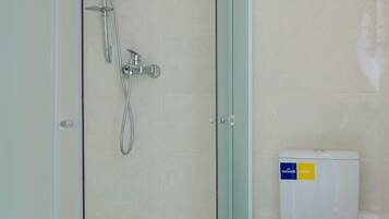 Un baño moderno con cabina de ducha de vidrio, inodoro y lavamanos.