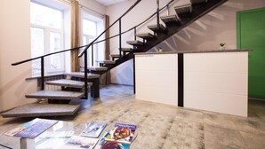 Una escalera con barandilla metálica que lleva a un rellano con una puerta verde.