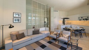 A modern living room with a sofa, armchairs, a coffee table, and a dining area with a table and chairs. - FLH Sá da Bandeira Luxury Apartment (Oporto)