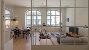 A modern living room with a sofa, TV, and dining area. - FLH Sá da Bandeira Luxury Apartment (Oporto)