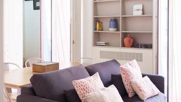 Un soggiorno moderno con un divano grigio scuro, un tavolo da pranzo in legno e una libreria bianca con libri e oggetti decorativi.