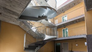 Monitasoinen, spiraalimainen portaikko, jossa on metallikaiteet. Se yhdistää rakennuksen eri kerrokset, ja rakennuksessa on keltaiset seinät ja betonikatto.