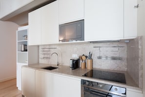 A modern kitchen with white cabinets, a built-in microwave, a stainless steel sink, and a dishwasher.