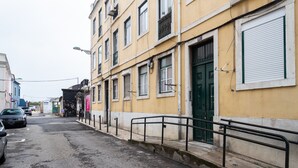 A narrow street with yellow buildings, a green door, and a closed shutter. - FLH Lx Factory Charming Place (Lisbon)