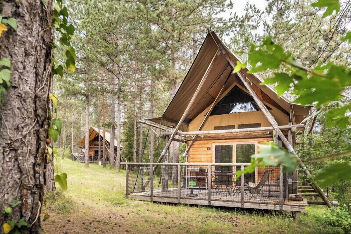 A cabin with a wooden exterior, a deck, and a fenced outdoor area.