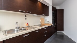 Eine moderne Küche mit dunklen Holzschränken, einer Edelstahlspüle und einem eingebauten Backofen.