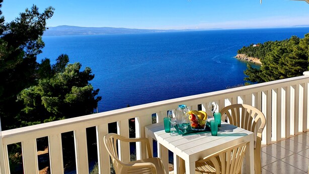 A balcony with a table set for two, overlooking a coastal view. - Villa Blue Adriatic (Omis)