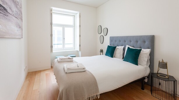 Et soveværelse med en stor seng, et vindue og et sengebord med en lampe.