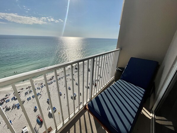 A balcony with a view of a beach and the sea.