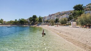 A beach with clear shallow water, people sunbathing, and buildings in the background. - RIA 2 - sea view 2+2 apt in Mastrinka, Trogir (Mastrinka)
