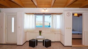 A room with a wooden ceiling, a view of the sea through a window, a bed, and a small table with a vase of flowers. - RIA 2 - sea view 2+2 apt in Mastrinka, Trogir (Mastrinka)