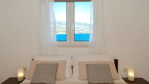 A bedroom with a bed, two bedside tables, and a window with a view of the sea. - RIA 2 - sea view 2+2 apt in Mastrinka, Trogir (Mastrinka)