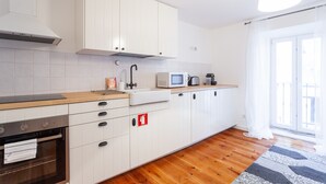 Una cocina moderna con armarios blancos, horno integrado, microondas y un lavabo.