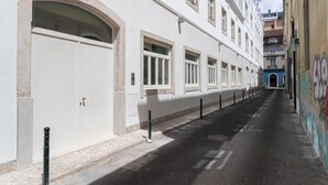 A narrow street with a white building featuring large windows and a door.