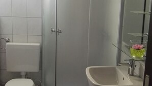 A bathroom with a toilet, a shower enclosure, and a sink. - Apartment Mojca near Bled (Zabreznica)