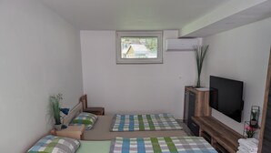 A room with two beds, a TV, a window with blinds, and a small desk with a lamp and a plant. - Apartment Mojca near Bled (Zabreznica)