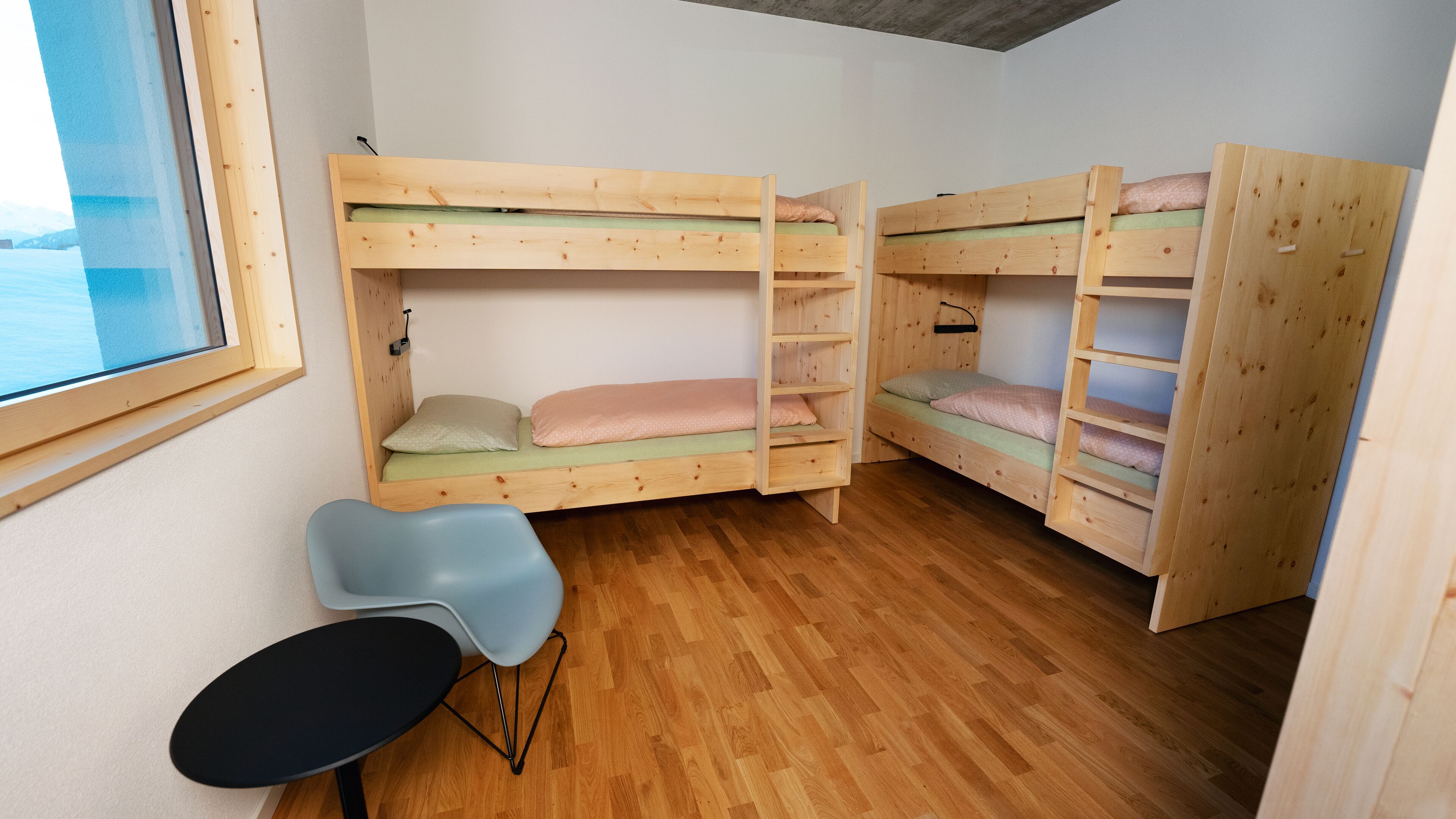 Een kamer met twee stapelbedden, een kleine tafel en een stoel.