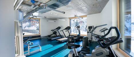 A gym with treadmills, elliptical machines, and a blue floor.