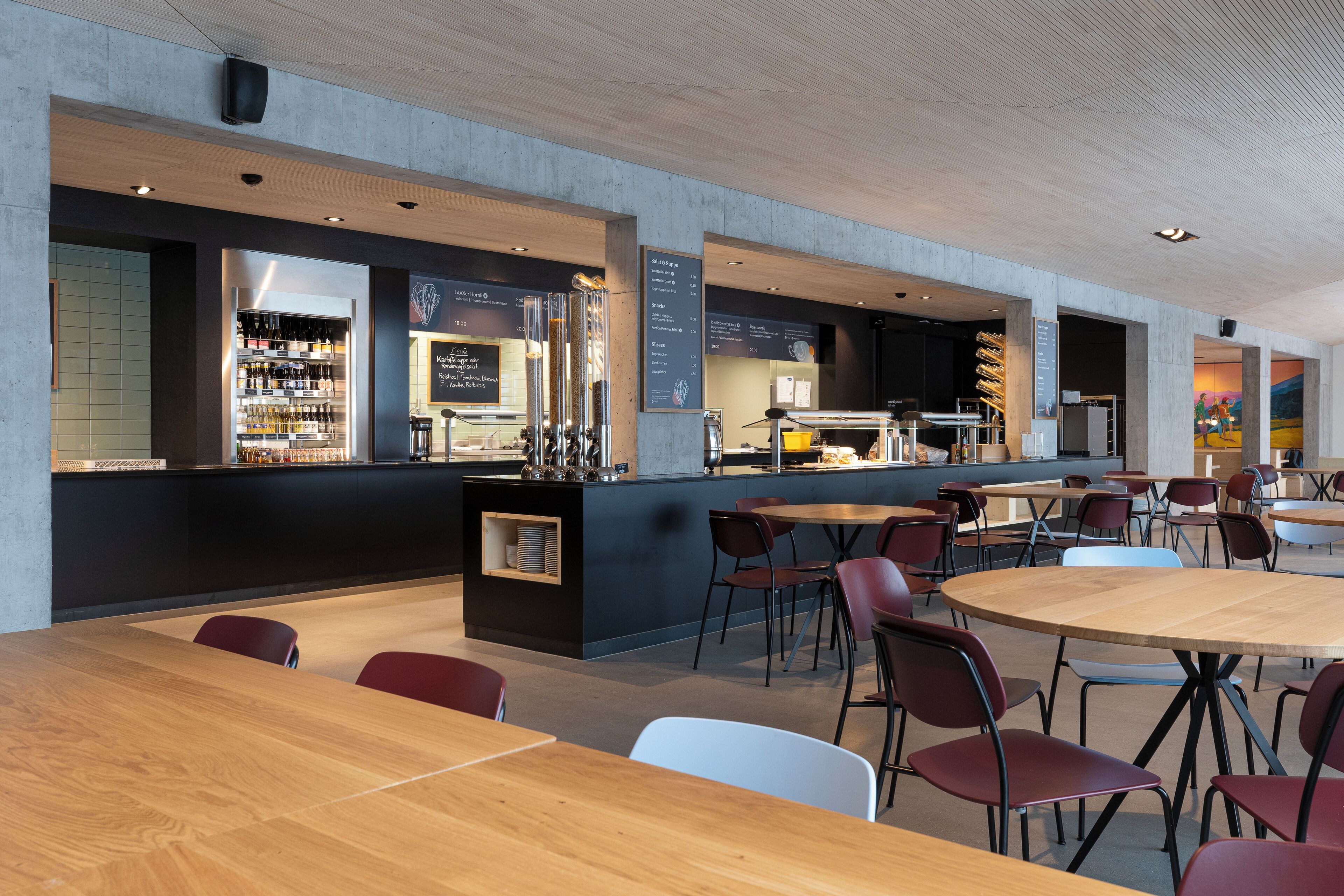 A modern cafe with wooden tables and chairs, a bar area with a menu, and a seating area with a view of the cityscape.