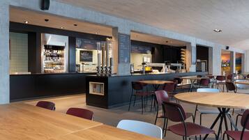 A modern cafe with wooden tables and chairs, a bar area with a menu, and a seating area with a view of the cityscape.