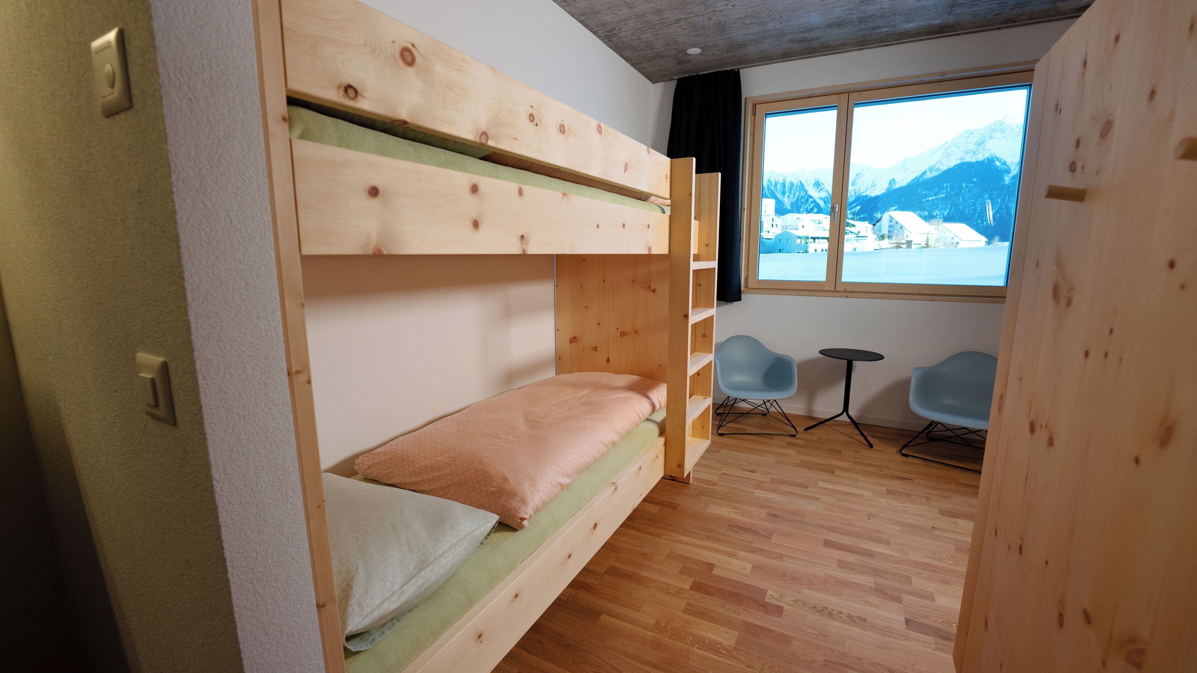 Ein Schlafzimmer mit Etagenbetten und Blick auf Berge durch ein großes Fenster.